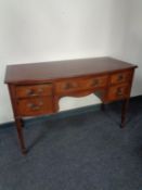 A 20th century inlaid mahogany bow fronted writing desk on raised legs, fitted five drawers.