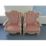 A pair of cream painted wood framed French style wing back armchairs upholstered in a pink button