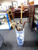 A blue and white oriental style stick stand containing assorted walking and shooting sticks
