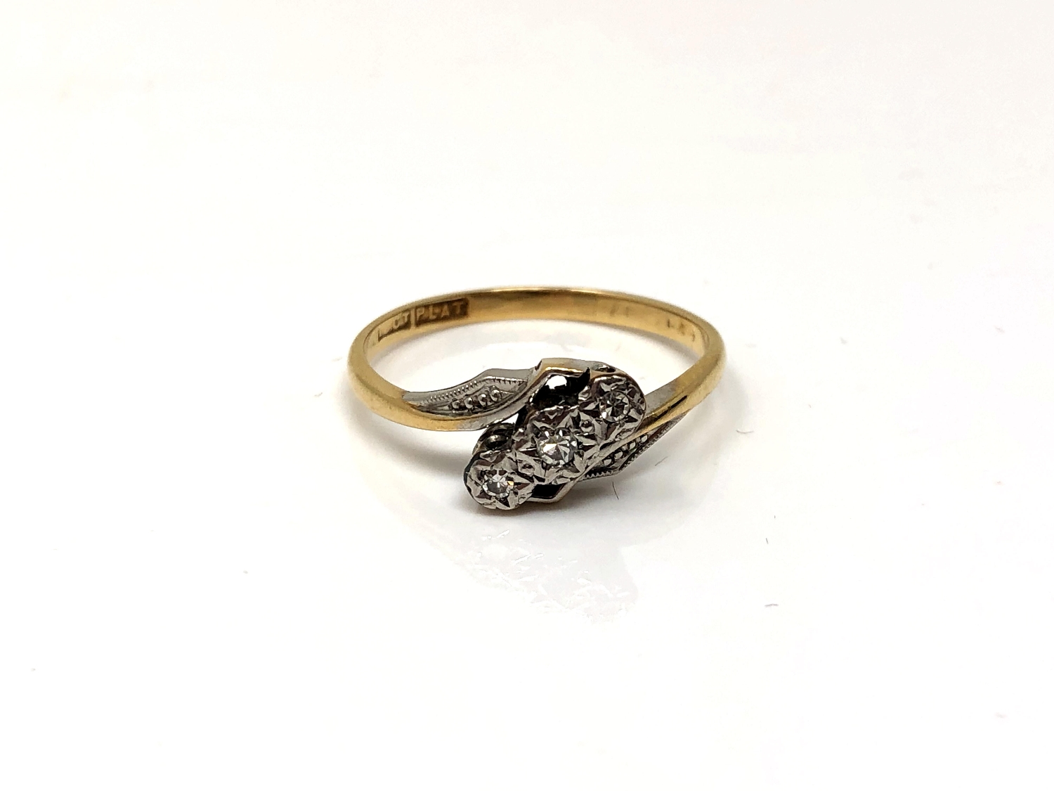 An 18ct gold and platinum three stone diamond crossover ring,