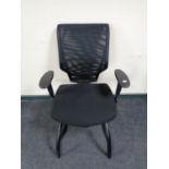 An office adjustable armchair upholstered in a black mesh fabric.