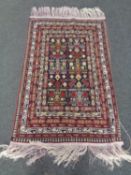 A fringed Afghan rug of geometric design.