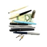 A group of fountain and ballpoint pens, £1 note, inert bullet, pocket watch keys.
