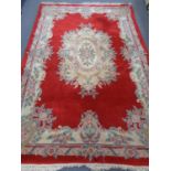 A Chinese fringed woolen rug on red ground.