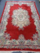 A Chinese fringed woolen rug on red ground.