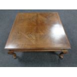 A contemporary square coffee table on cabriole legs in walnut finish