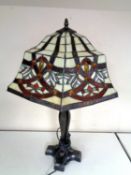 A cast iron table lamp together with a Tiffany style leaded glass shade.