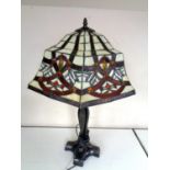 A cast iron table lamp together with a Tiffany style leaded glass shade.