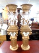 A pair of white and gilt composite cherub planters on stands