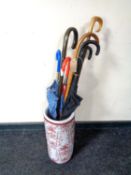 A china stick pot containing a collection of assorted walking sticks and umbrellas.