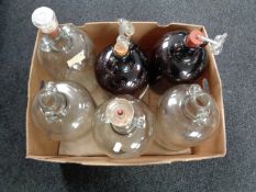 A box containing six glass demijohns.