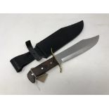 A modern bowie knife with wooden grip, blade length 25 cm, in black leather sheath.