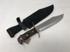 A modern bowie knife with wooden grip, blade length 25 cm, in black leather sheath.