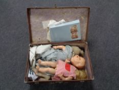 A mid 20th century luggage case containing plastic and cloth dolls, doll's clothes.