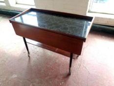 A mid 20th century teak two tier tea trolley on castors with flap side