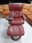 A Stressless Burgundy leather swivel adjustable armchair with lap tray and stool.