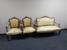 A three piece carved beech framed French style salon suite upholstered in a gold fabric.