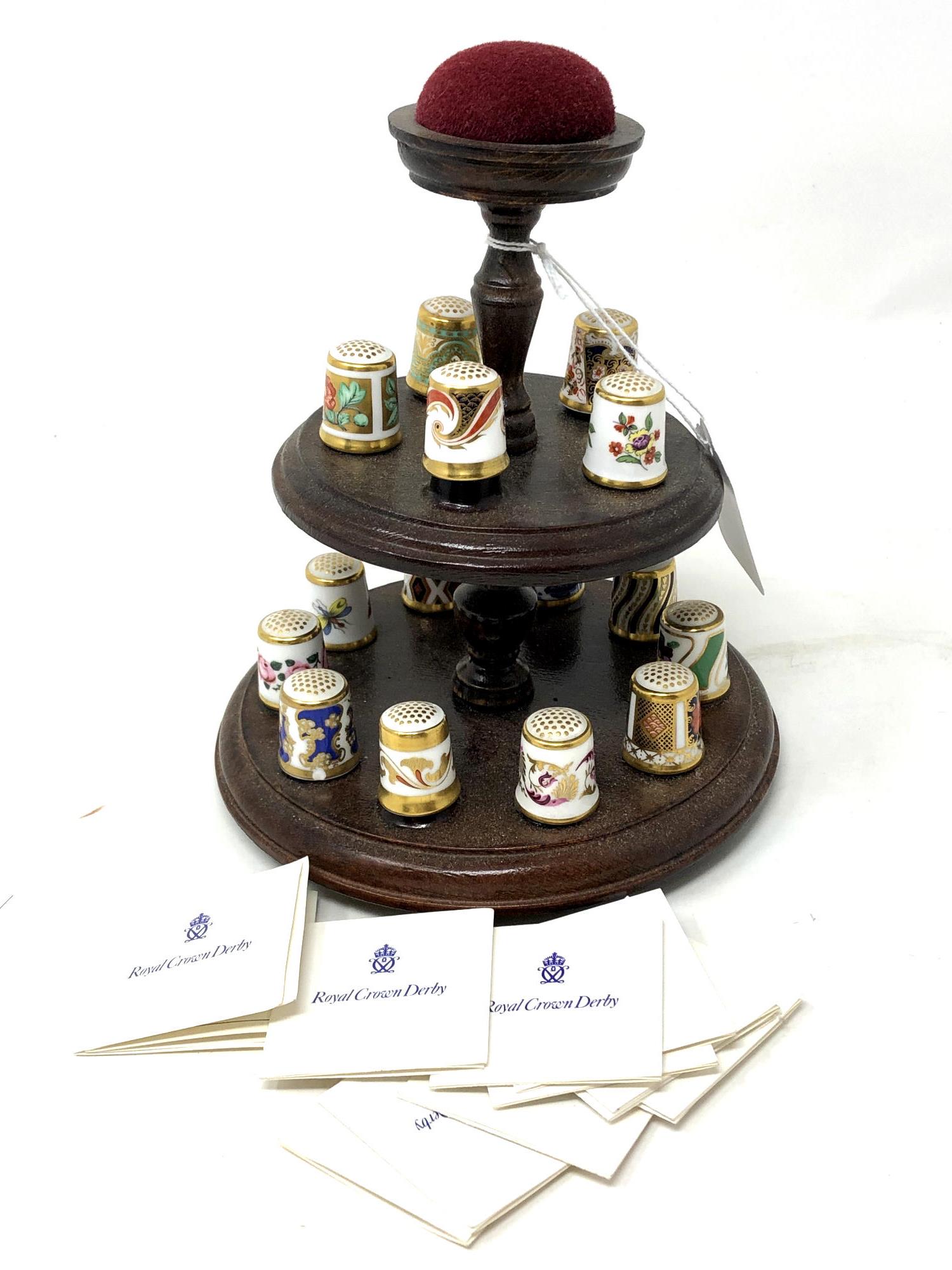 A collection of fifteen Royal Crown Derby porcelain thimbles on display stand with certificates