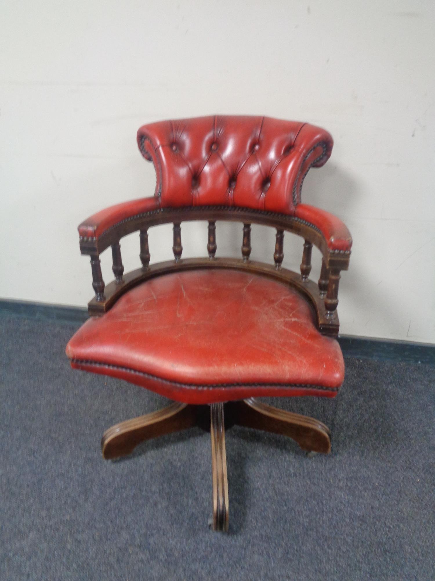 A captain's desk chair upholstered in a red button leather.