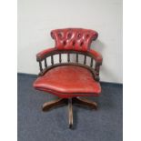 A captain's desk chair upholstered in a red button leather.