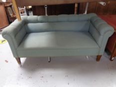 A 20th century low back settee upholstered in a green fabric.