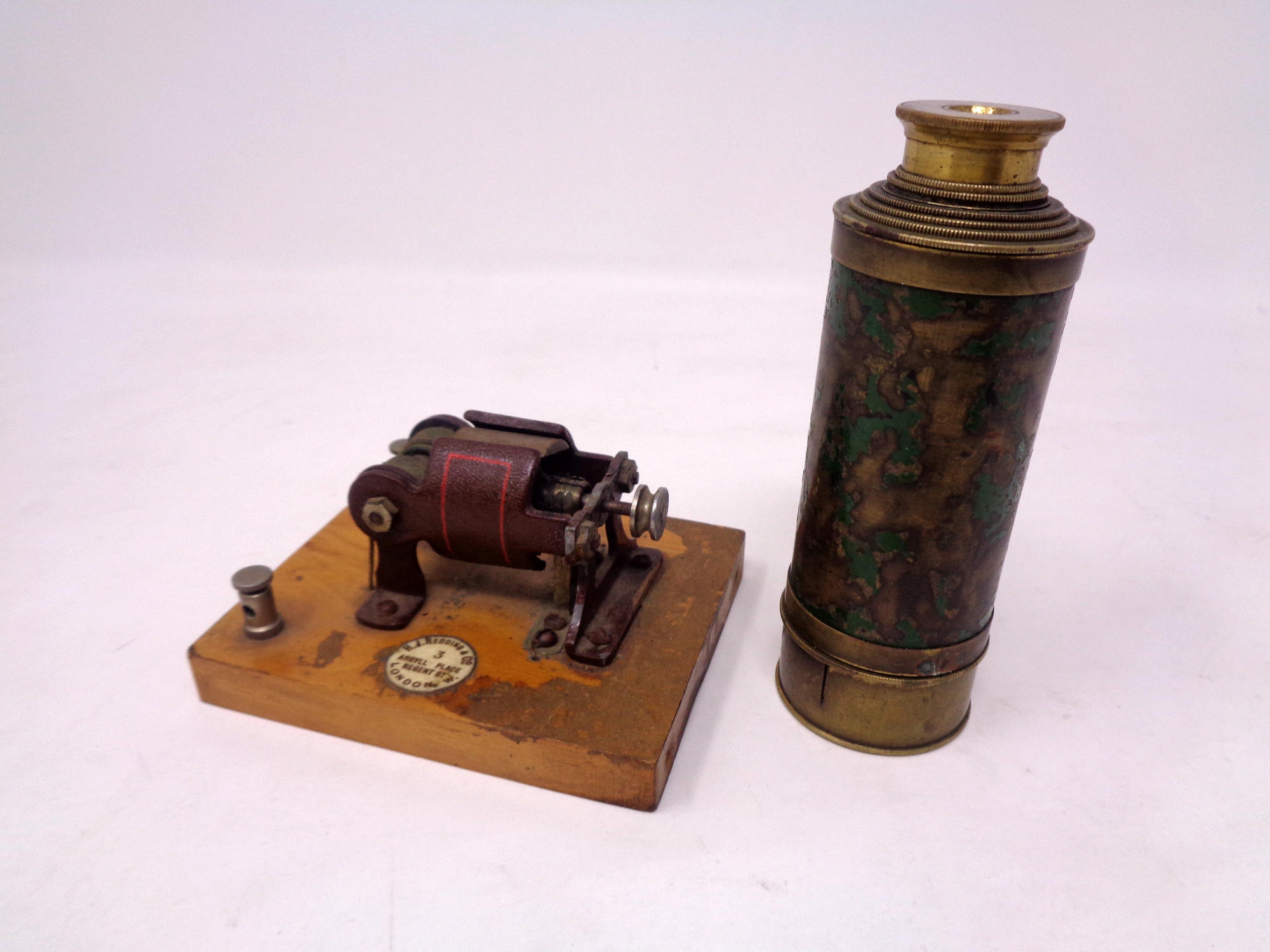 A brass pocket telescope together with a model dynamo mounted on a board by H. J.