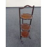 An Edwardian mahogany three tier pie crust edge folding cake stand.