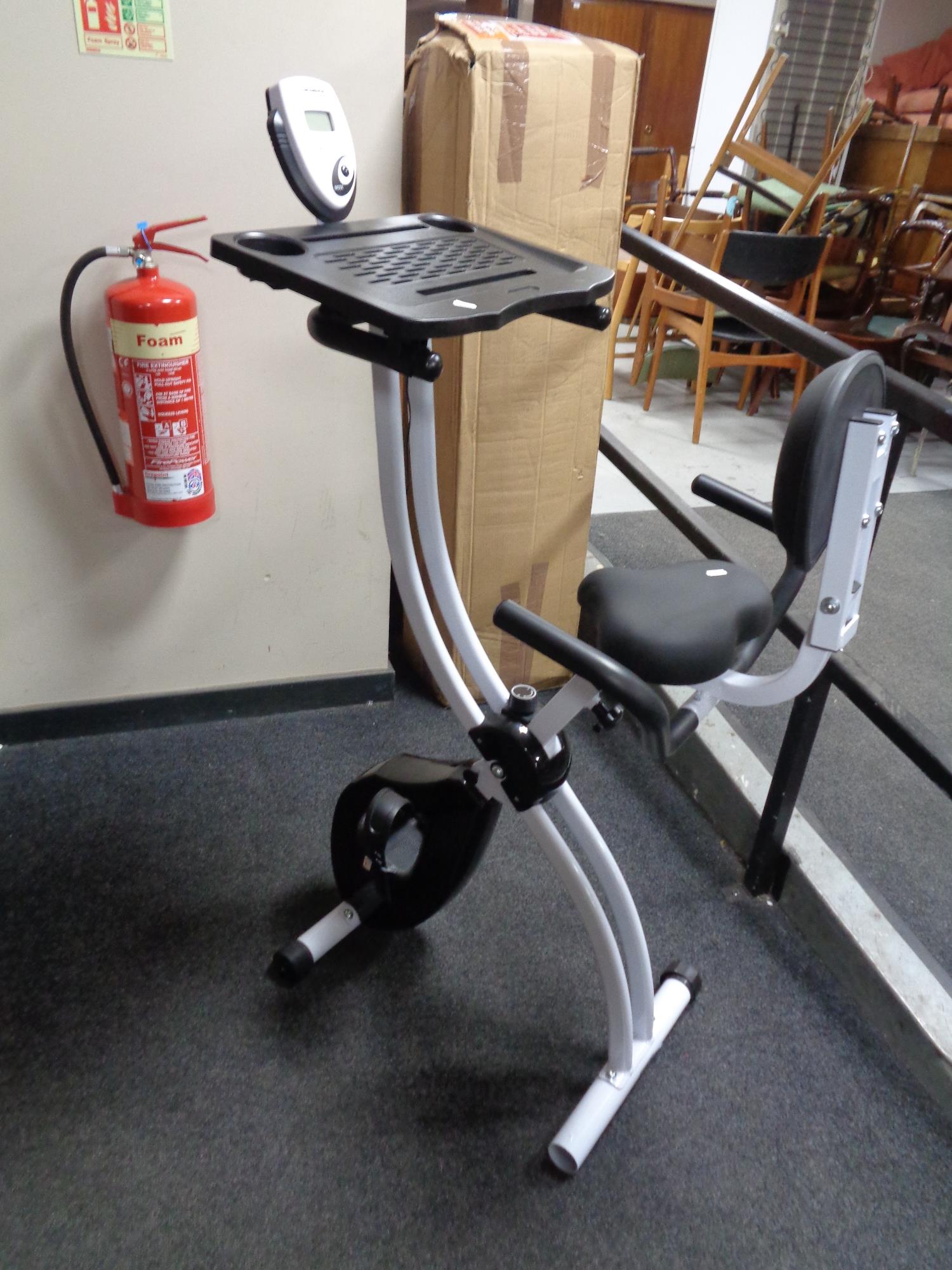 A folding Confidence Fitness exercise bike with laptop tray.