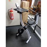 A folding Confidence Fitness exercise bike with laptop tray.