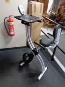 A folding Confidence Fitness exercise bike with laptop tray.