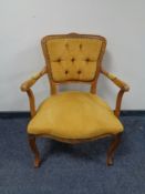 A carved beech framed armchair upholstered in a gold button dralon.