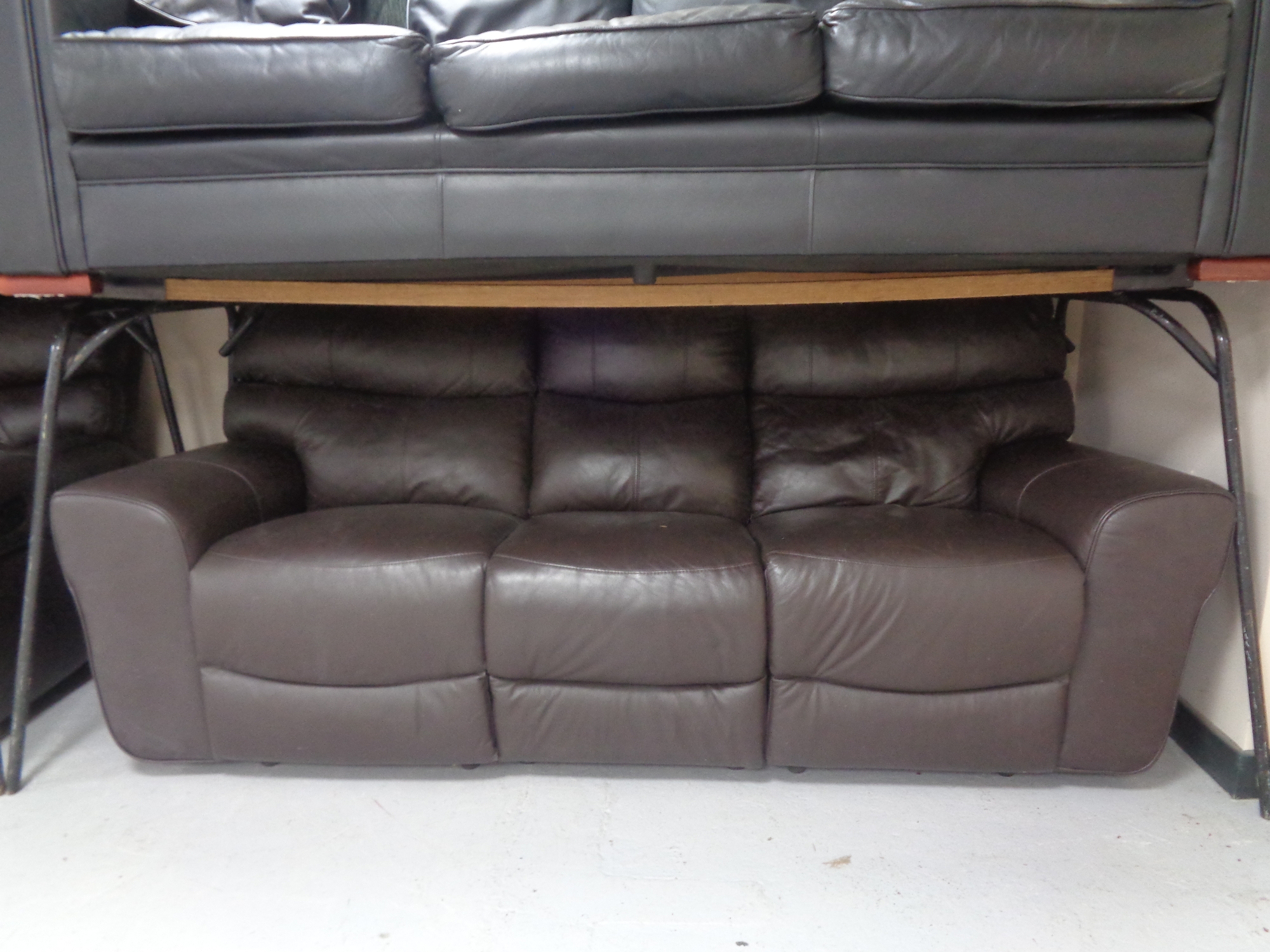 A brown leather manual reclining three seater settee with matching two seater settee.