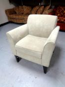 A contemporary armchair upholstered in a beige fabric