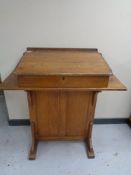 An antique oak clerk's desk fitted cupboard to rear