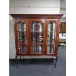 A triple door bookcase with brass mounts on Queen Anne style legs.