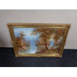 A gilt framed oil on canvas depicting a river through a wooded landscape.