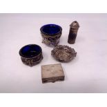 An ornate silver salt with blue glass liner, another similar salt, silver repousse dish,