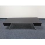 A rectangular contemporary black ash coffee table on metal legs.