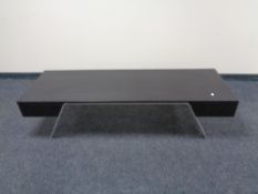 A rectangular contemporary black ash coffee table on metal legs.