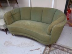 A shaped Art Deco settee upholstered in a green fabric.