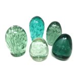 Five green glass dumps with bubble and flower inclusions.
