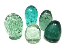 Five green glass dumps with bubble and flower inclusions.