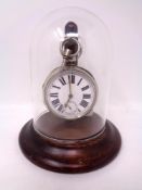 A key wound pocket watch under glass dome