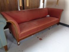An early 20th century mahogany framed three seater settee upholstered in a red fabric.