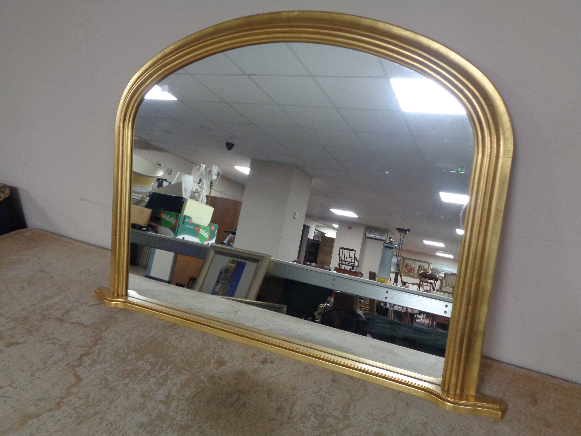 A contemporary gilt framed arch topped overmantel mirror.