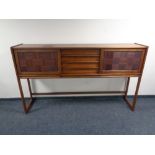 A six piece teak dining room suite comprising sliding door sideboard on raised legs,