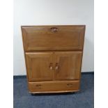 An Ercol elm cabinet fitted with cupboards and a drawer beneath