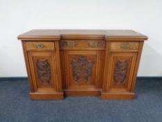 A late Victorian carved walnut inverted breakfront sideboard