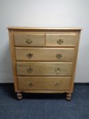 A pine chest of five drawers with brass bow handles