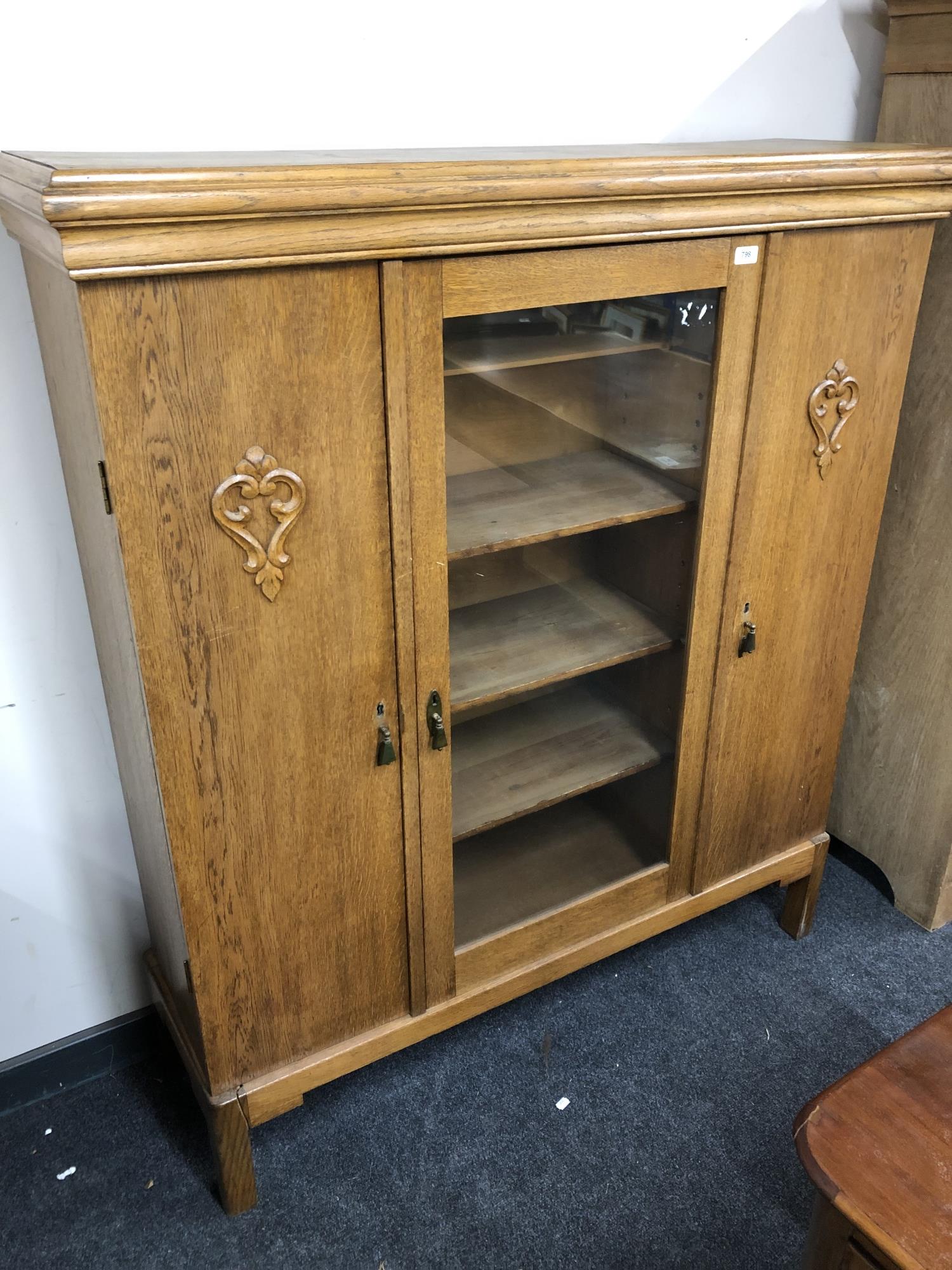 A continental glazed oak triple door display cabinet